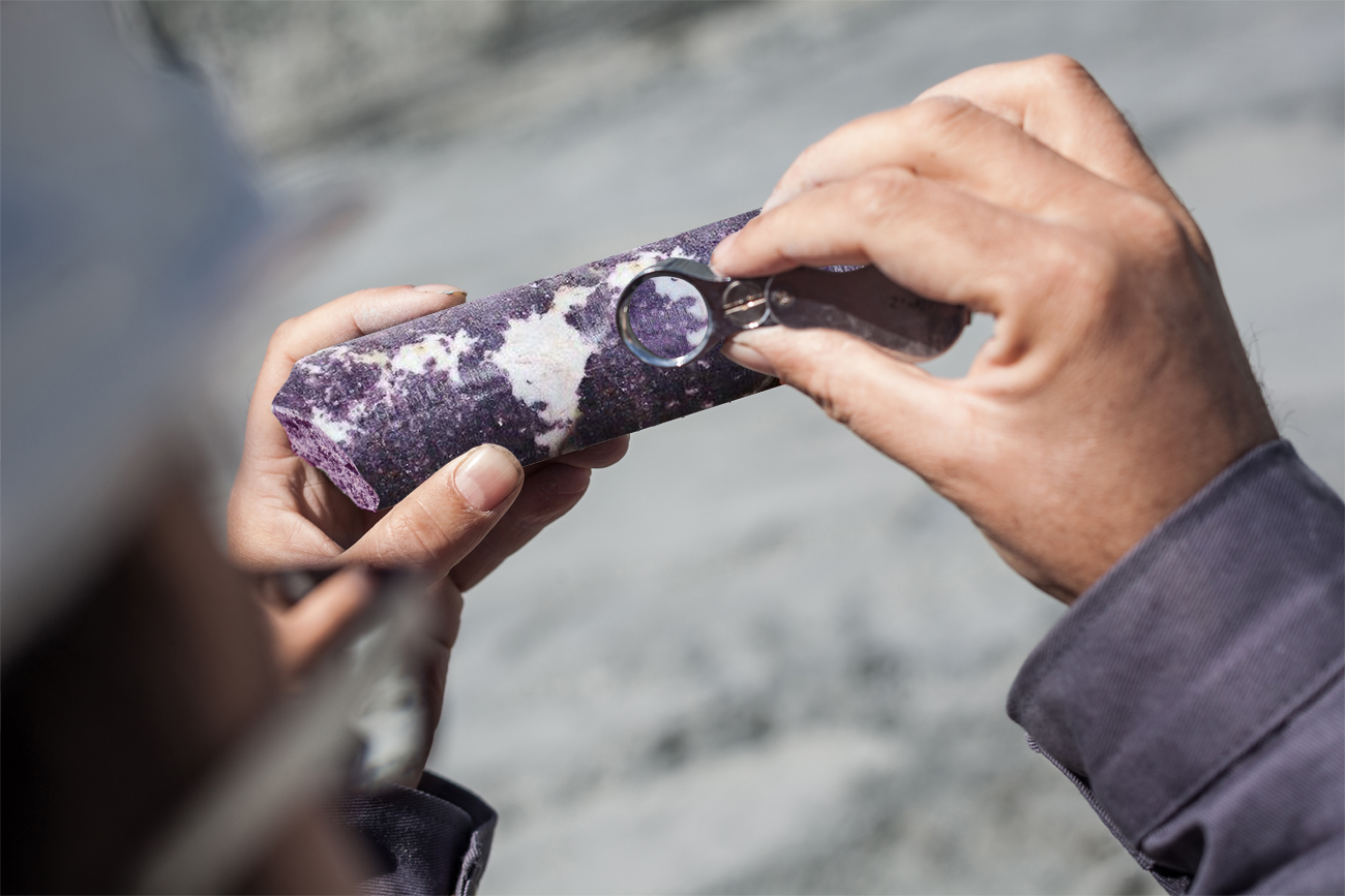 Engineer examining ore specimens with magnifying glass
